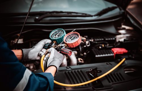 Close up hand of auto mechanic using measuring manifold gauge check the refrigerant and filling car air conditioner for fix and checking for repair service support maintenance and car insurance.